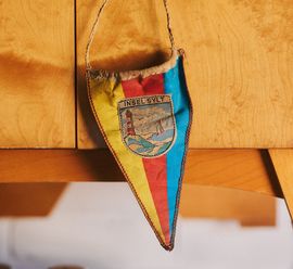 Bunter Wimpel mit der Aufschrift "Insel Sylt" und Leuchtturm-Motiv.
