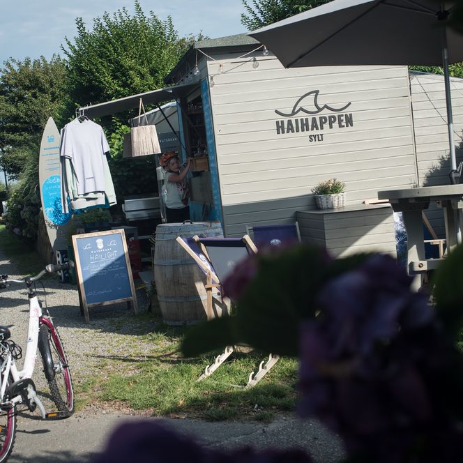 Foodtruck „Haihappen Sylt“ mit Deko und Liegestühlen auf grünem Gelände.