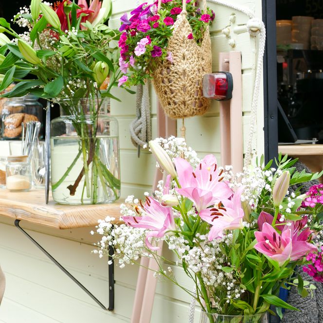 Frische Blumen in Vasen und Blumenampel vor Caféstand