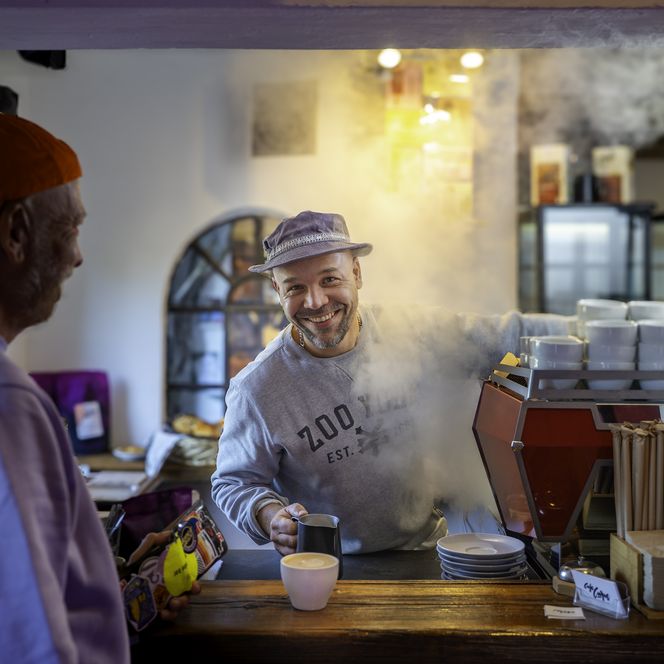 Barista bereitet lächelnd Kaffee im Café Curve in Wenningstedt-Braderup zu.