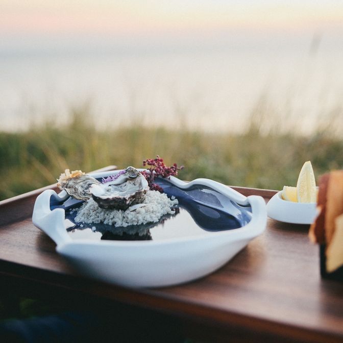 Austern auf Porzellanteller mit Meerblick bei Sonnenuntergang