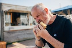Mann isst Snack vor rustikalem Gebäude bei