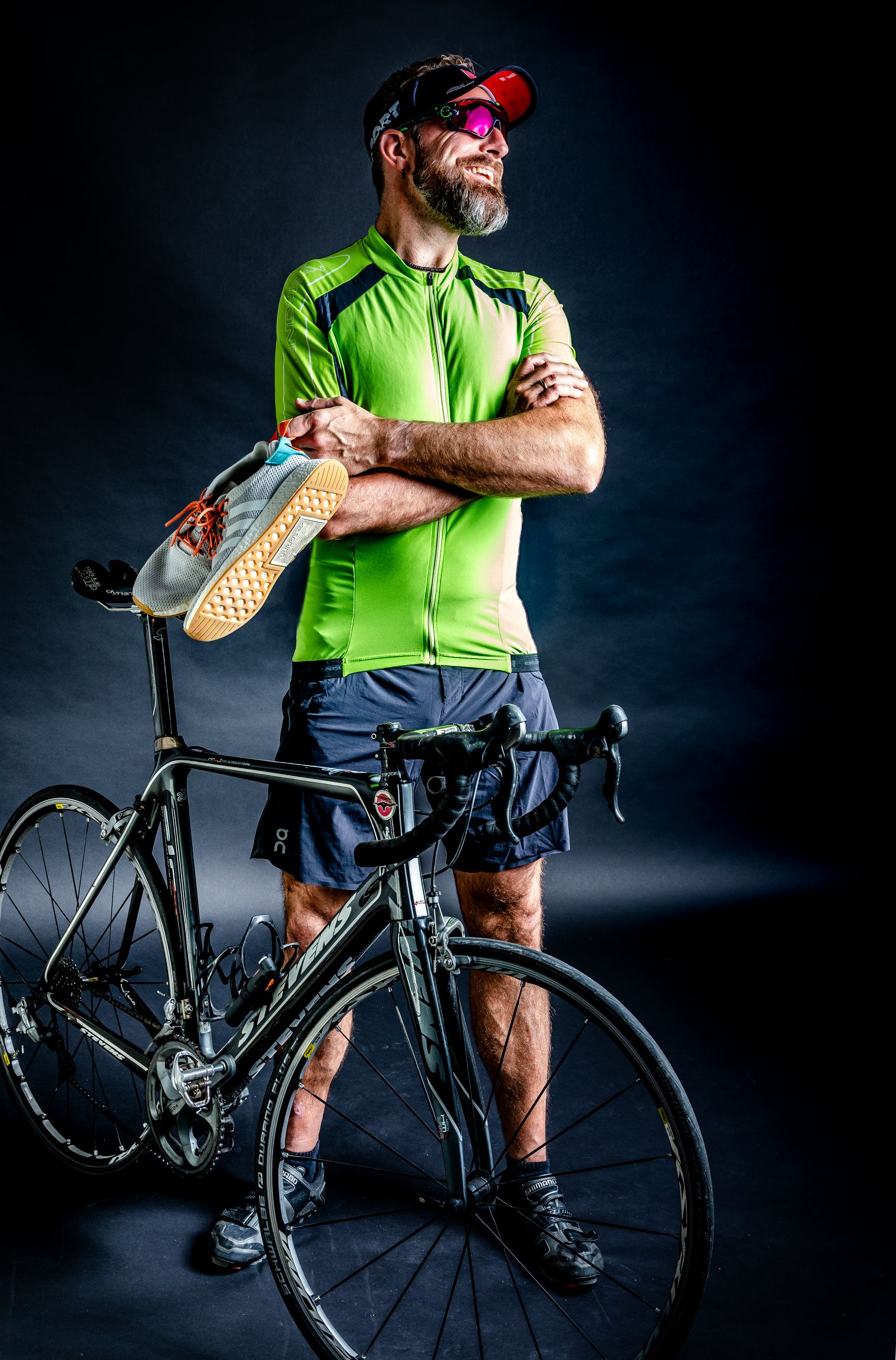 Dietmar Priewe im Radoutfit hinter Rennrad, Laufschuhe auf dem Sattel.