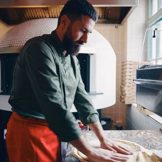 Ein Pizzabäcker formt Teig auf einer bemehlten Arbeitsplatte im Ciao Maria in Wenningstedt.