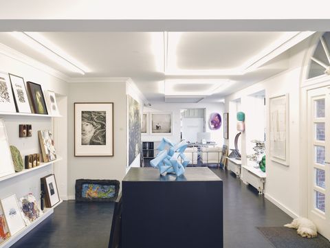 Helle Galerie mit moderner Kunst, Skulpturen und einem Hund am Eingang