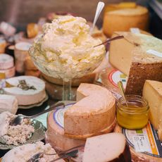 Käsetheke mit verschiedenen Käsesorten, Butter und Honig.