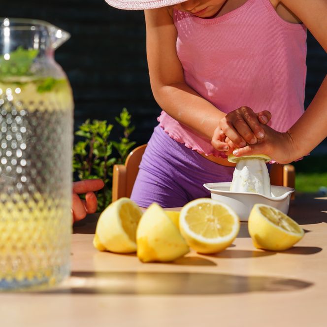 Kind presst Saft aus einer Zitronenhälfte