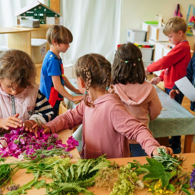 Kinder an Tischen mit Blumen und Papier