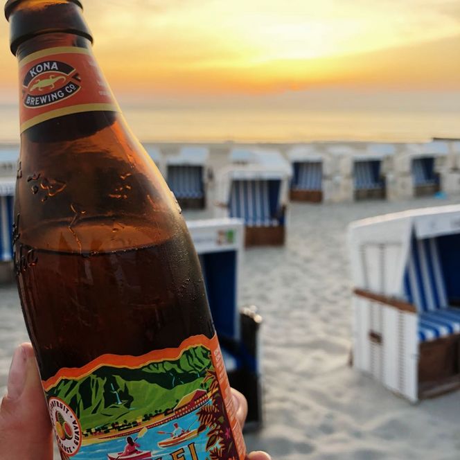 Bierflasche am Strand bei Sonnenuntergang und Strandkörben