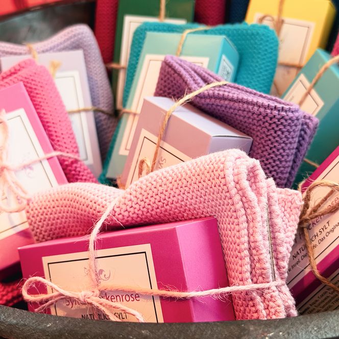 Bunte Seifenboxen mit gestrickten Waschlappen im Korb 