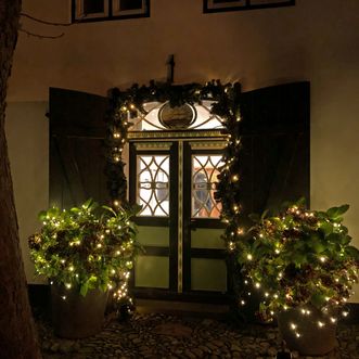 Festlich geschmückter Eingang eines Friesenhauses auf Sylt Beleuchteter Eingang eines Friesenhauses mit Lichterketten und geschmückten Pflanzen.