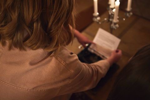 Zwei Personen lesen gemeinsam einen Hinweiszettel bei Kerzenschein.