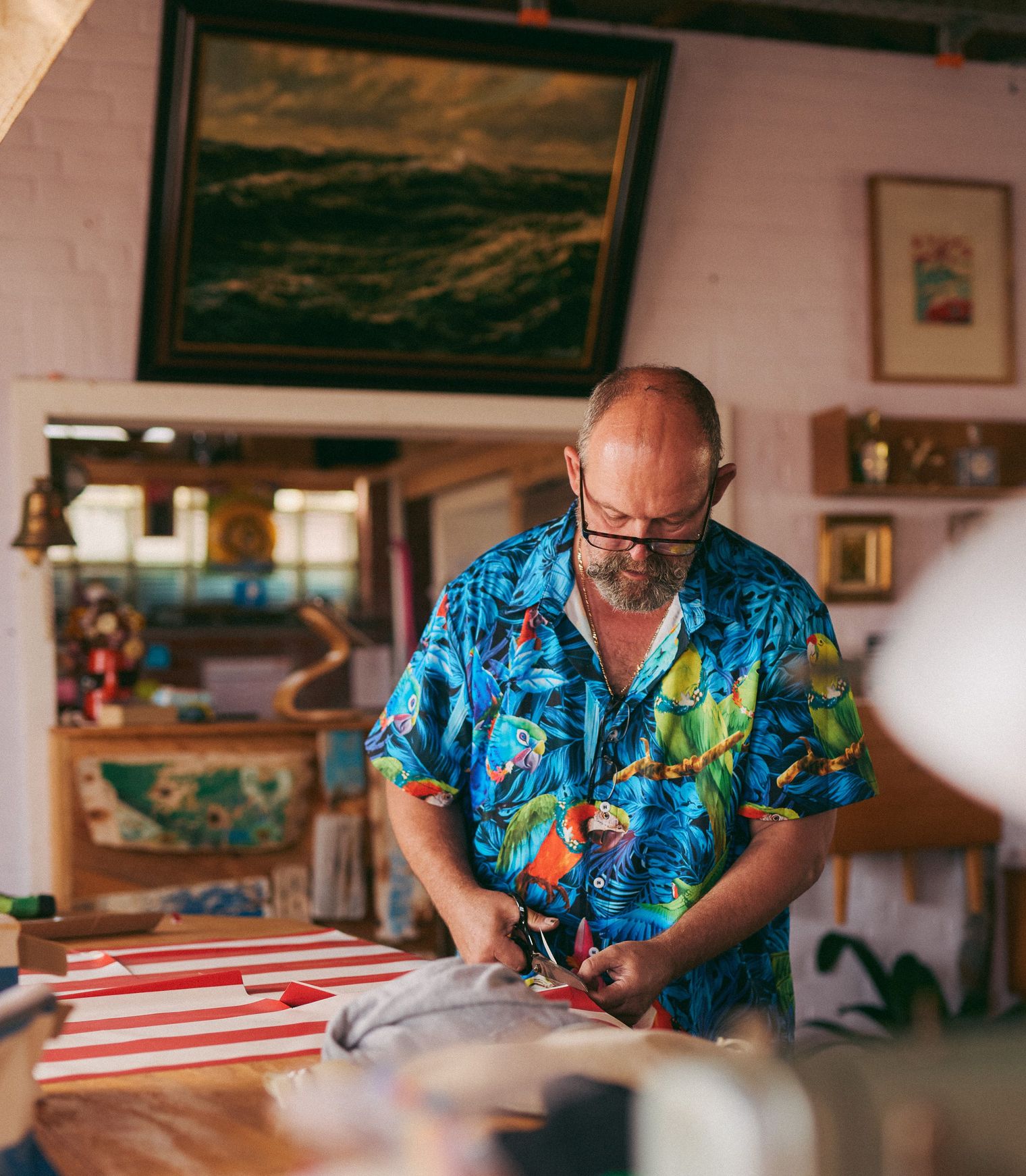 Mann in tropischem Hemd schneidet Stoffstreifen in einem maritim dekorierten Raum.