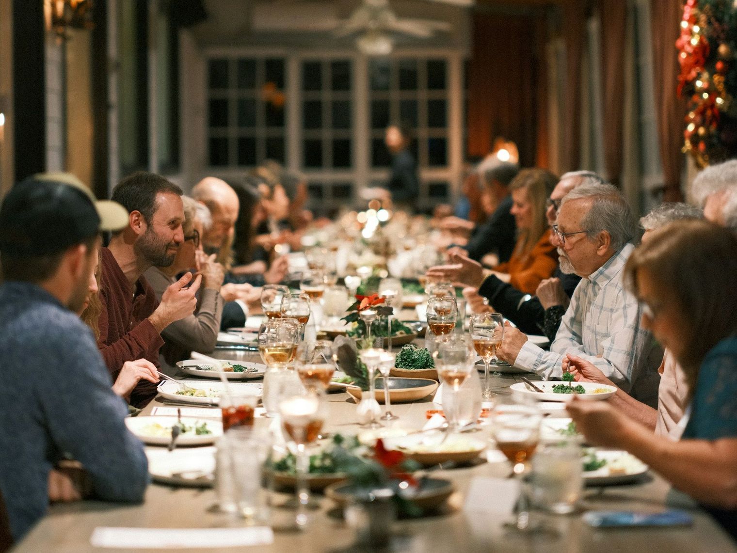 Viele Menschen sitzen an langer Tafel und essen gemeinsam.