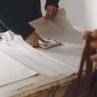 Sorgfältig verpackt – Handwerk mit Liebe zum Detail Hände verpacken eine bemalte Fliese in weißes Papier