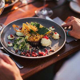 Gourmetteller mit Avocadocreme, Granatapfel und dekorativen Zutaten im Abendlicht.