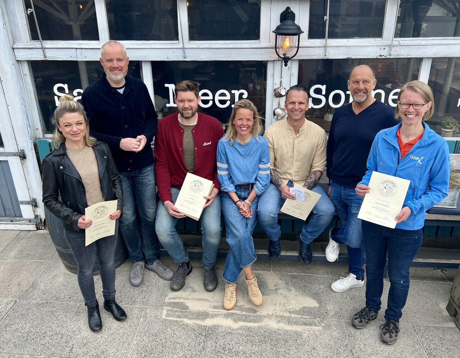 Sieben Personen mit Urkunden vor einem Gebäude, Projektauftakt „Lebenswertes Sylt“