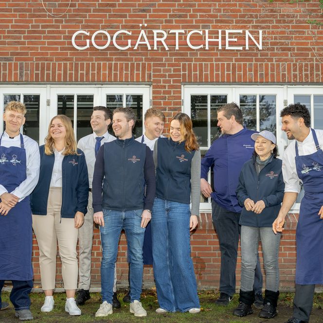 eam des Gogärtchen lacht gemeinsam vor der Backsteinfassade des Restaurants.