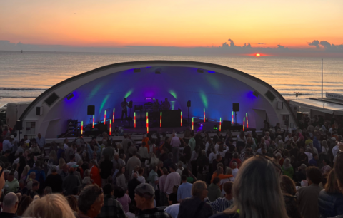 Open-Air-Konzert bei Sonnenuntergang am Strand mit vielen Menschen