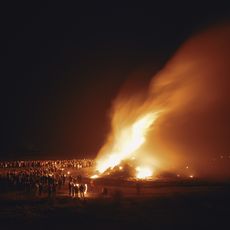 Menschen versammeln sich abends um großes Biikefeuer auf Sylt