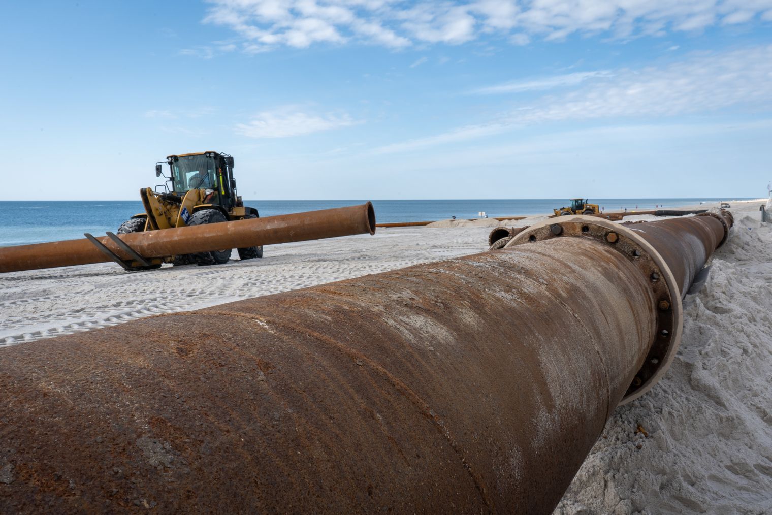 Bagger verlegen die Rohre am Strand für die Sandvorspülung