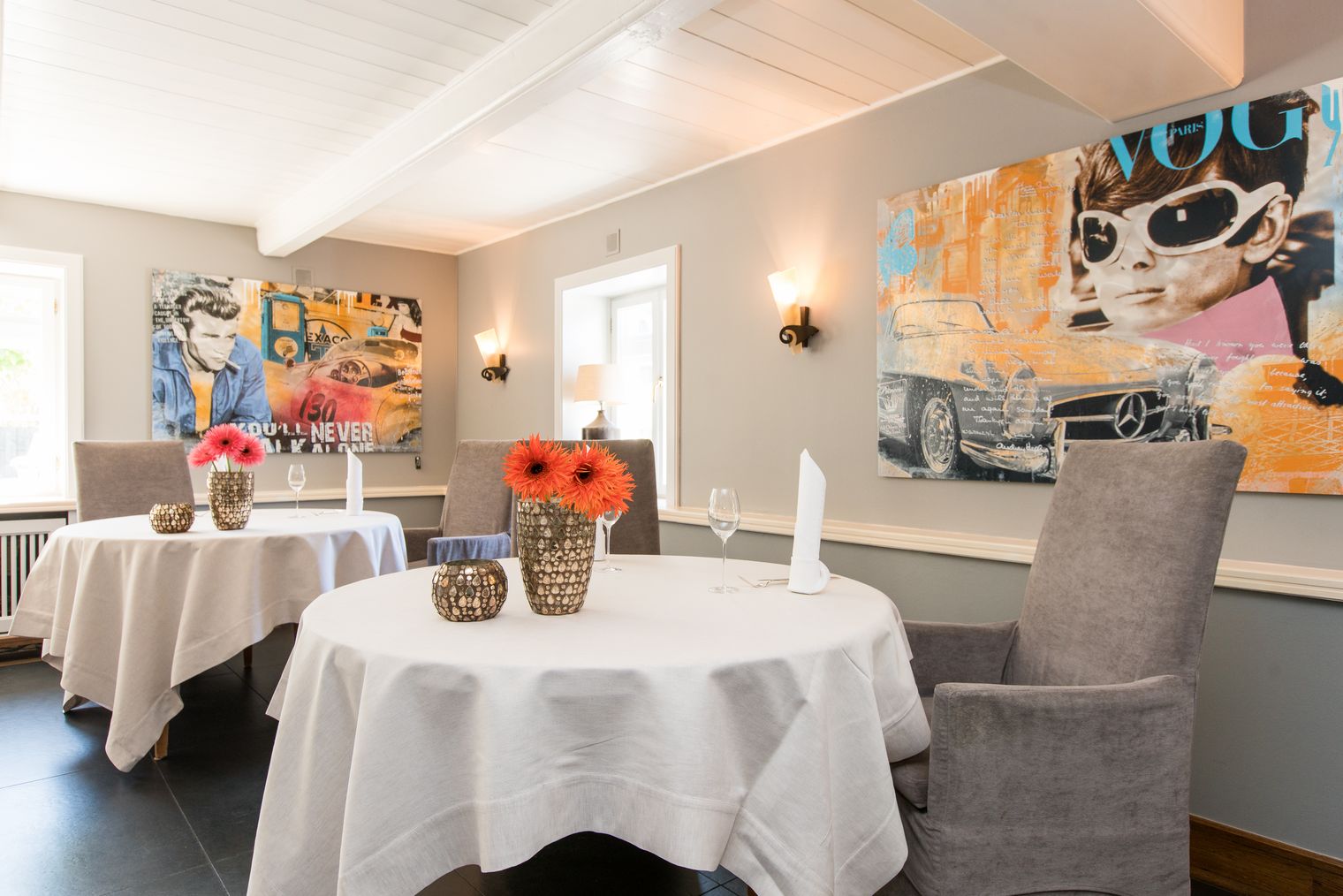 Edles Restaurant mit runden Tischen, Wandkunst und Blumenvasen im Landhaus Stricker