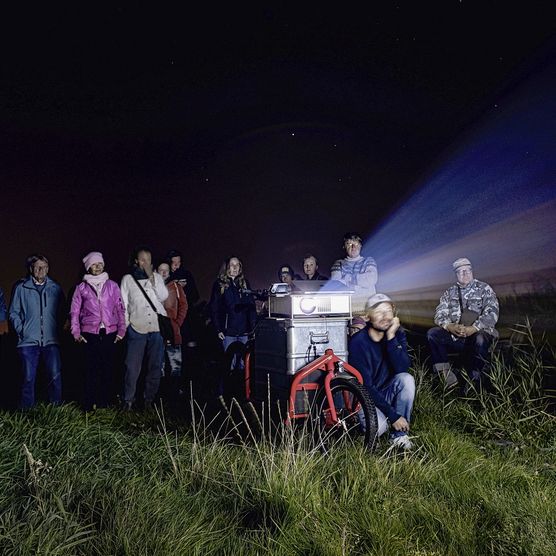 Menschen bei Nacht schauen Film, projiziert von einem Lastenrad.