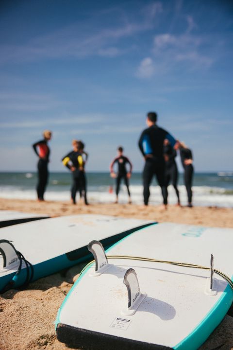  Eine Gruppe von Surfern steht am Strand, Surfbretter liegen im Sand. 