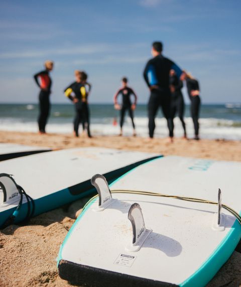 Un groupe de surfeurs se tient sur la plage, des planches de surf posées dans le sable.