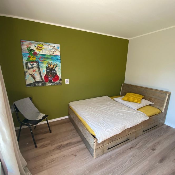 Azubi-Zimmer mit gemütlichem Bett, moderner Farbgestaltung und kreativer Wandkunst.