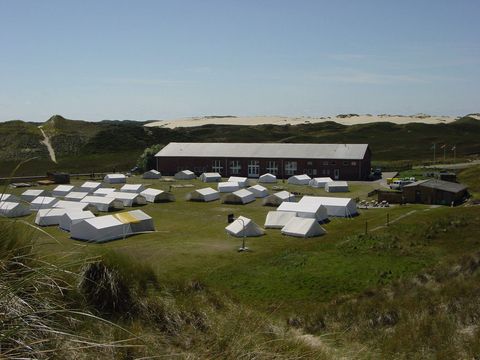 Der Jugendzeltplatz Möwenberg in List auf Sylt mit mehreren Zelten und einem großen Backsteinhaus in einer Dünenlandschaft.