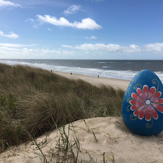 Großes, bemaltes Osterei in den Dünen am Strand von Westerland.