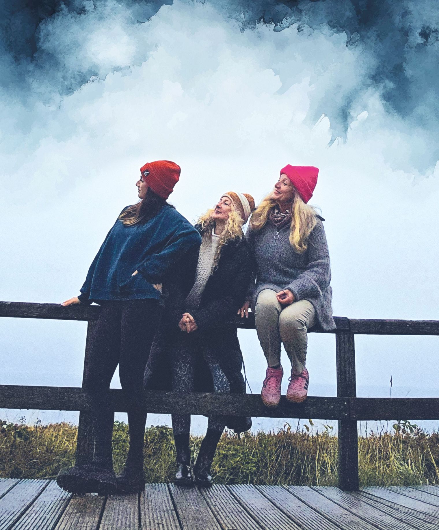 Drei Frauen sitzen auf einem Holzgeländer und schauen gemeinsam in den Himmel.