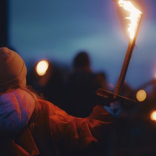 Kleines Mädchen mit Fackel beim Biikebrennen in der Dämmerung