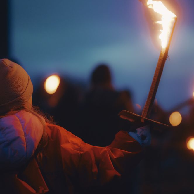 Kleines Mädchen mit Fackel beim Biikebrennen in der Dämmerung