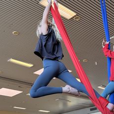 Kind macht Akrobatik am roten Vertikaltuch