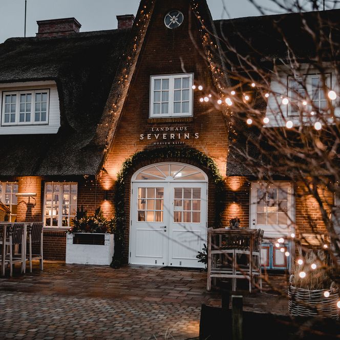 Beleuchtetes Landhaus Severin’s in Morsum mit Lichterketten im Abendlicht.