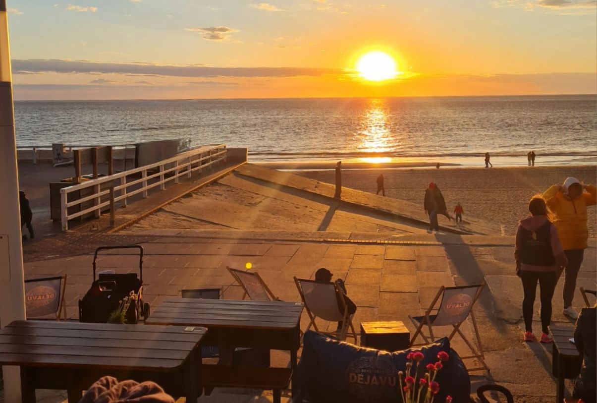 Sonnenuntergang am Meer mit Terrasse und Menschen