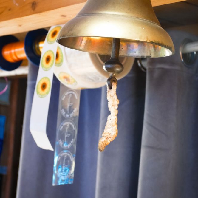 Kleine Metallglocke hängt an einer Schnur im Innenraum. 