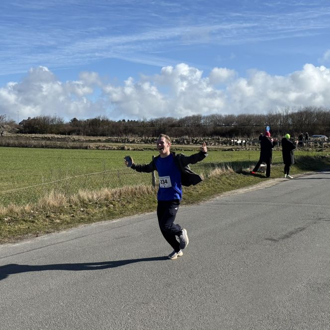 Mann joggt freudestrahlend und hebt die Arme