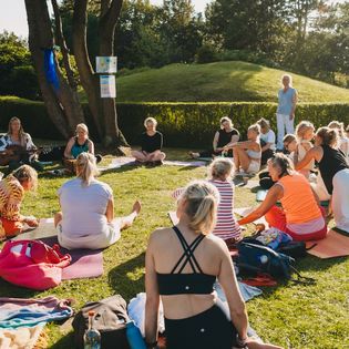 Gruppe sitzt im Kreis bei Yoga im Park