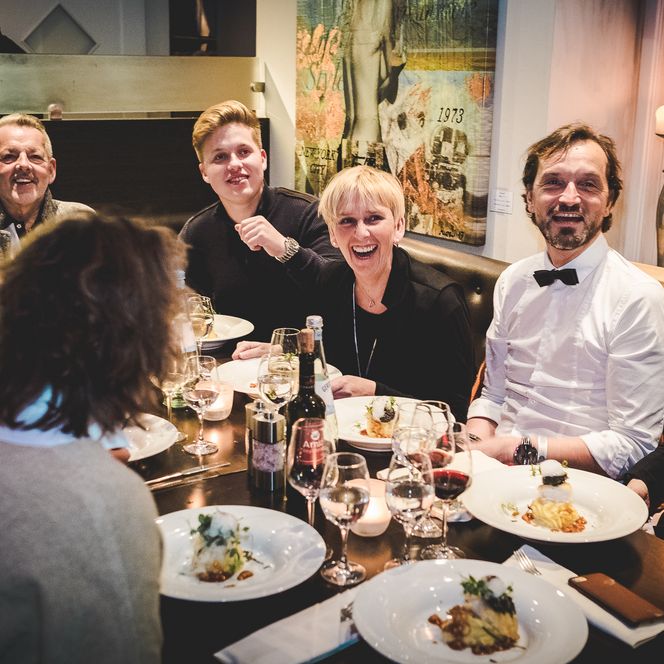 Gäste lachen gemeinsam beim Abendessen in einem Restaurant