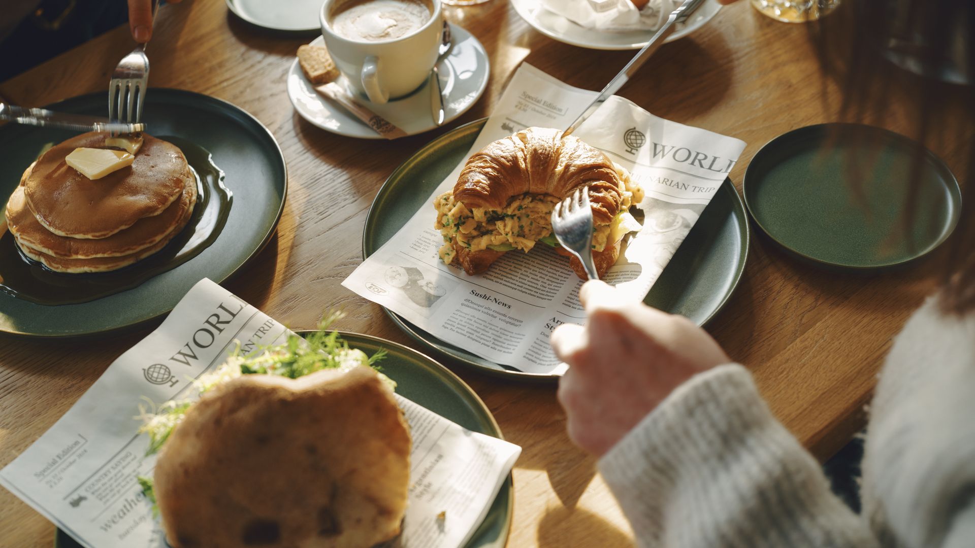 Frühstück mit Pancakes, Croissant-Sandwich und Getränken
