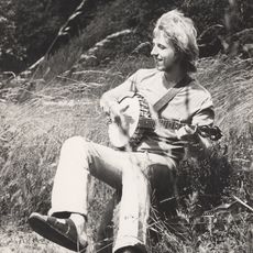 Henner Krogh sitzt im Gras und spielt Banjo.