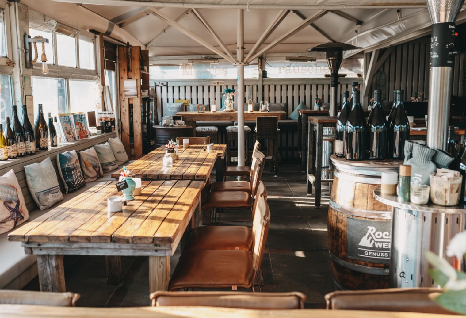 Innenraum eines rustikal-maritim eingerichteten Bistros mit Holztischen und Deko