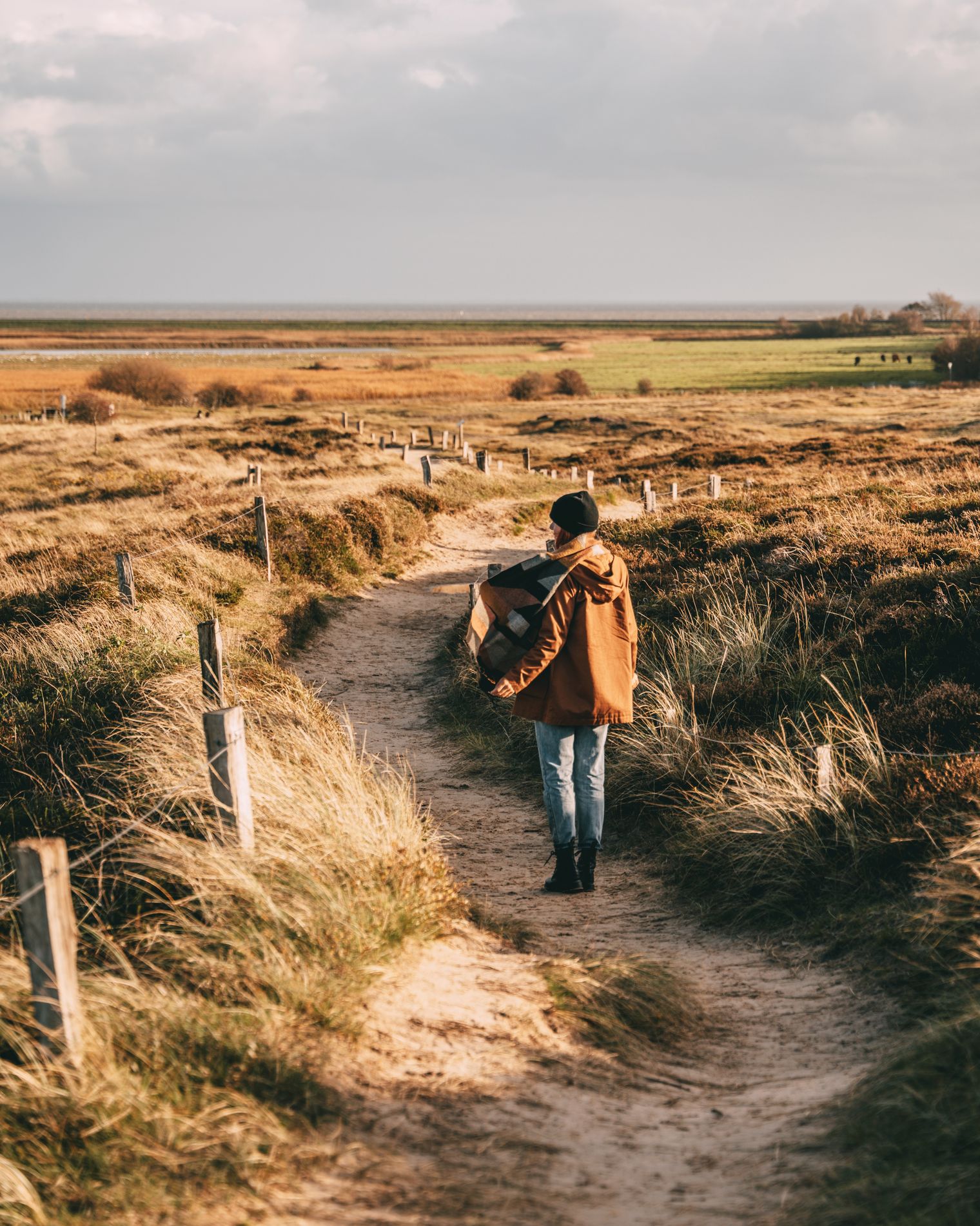 Spaziergang durch die herbstliche Dünenlandschaft am Morsum Kliff mit Blick auf grüne Felder und das Wattenmeer.