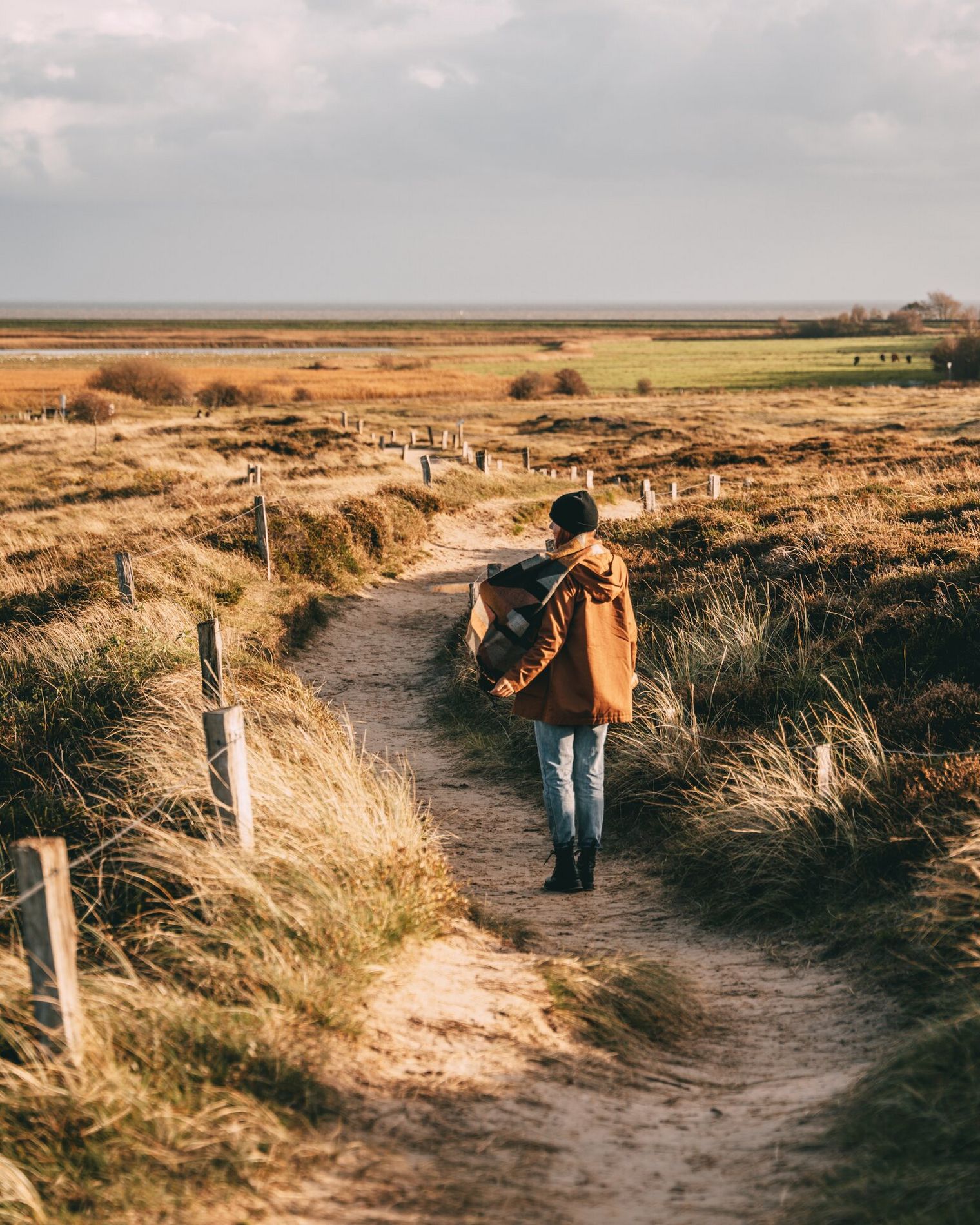 Spaziergang durch die herbstliche Dünenlandschaft am Morsum Kliff mit Blick auf grüne Felder und das Wattenmeer.