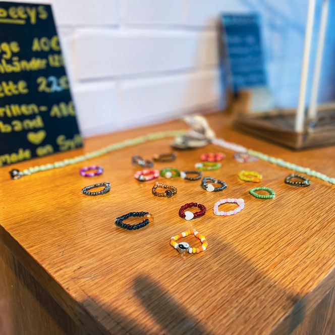 Bunter Perlenschmuck und Preistafel im Surfhouse-Shop. Barrierefreiheit