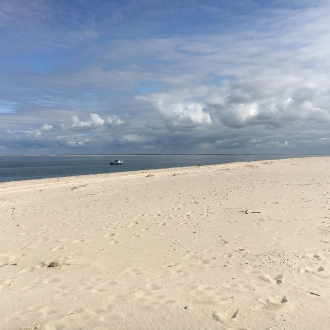 Weißer Sandstrand mit Meer und Boot am Ellenbogen Sylt.