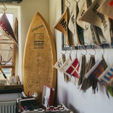 Wimpel an einer Wand, ein gelbes Surfbrett und ein Plattenspieler in einem kreativ gestalteten Raum.